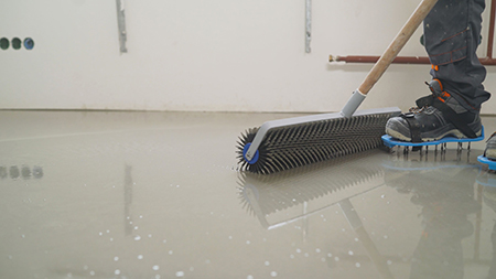 Leveling the screed with a roller. Interior of apartment under construction. Roller application. Mirror smooth surface of the floor. Floor covering with self leveling cement mortar